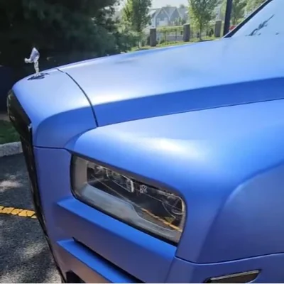 The headlight and front fender of a blue Rolls-Royce Cullinan