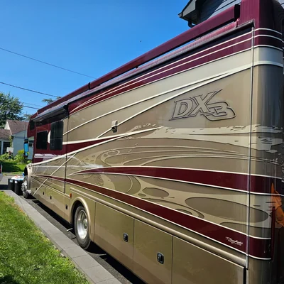 A Class A motorhome in maroon and gold, parked on a residential street