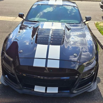 A Ford Mustang Shelby GT500 head-on, twin white stripes over dark paint