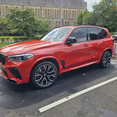 A red BMW X5 M, front three-quarter, paint clean and reflective
