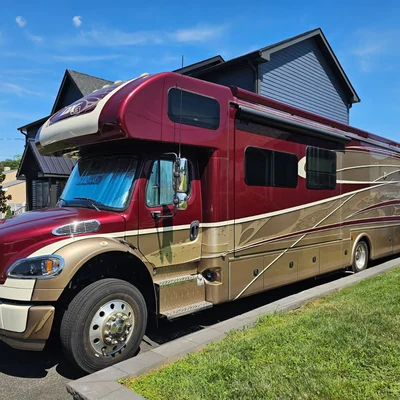 A Super C motorhome in maroon and gold on a residential lot