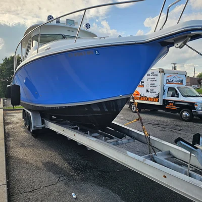 A blue sportfishing boat on a trailer with the Rashine box truck alongside