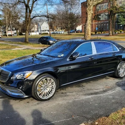 A black Mercedes-Maybach S-Class detailed curbside, chrome wheels and paint reflecting cleanly