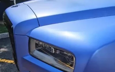 The headlight and front fender of a blue Rolls-Royce Cullinan