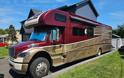 A Super C motorhome in maroon and gold on a residential lot