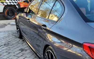 A dark BMW M5 alongside the Rashine Mobile trailer